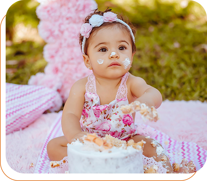 A baby sitting in front of a cake with pink decorations.