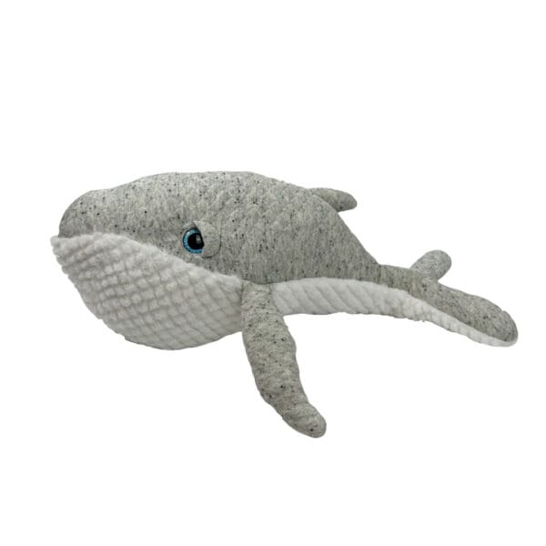 A stuffed whale is laying down on the ground.