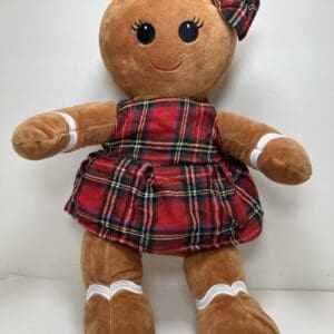 A stuffed gingerbread girl doll wearing plaid dress.