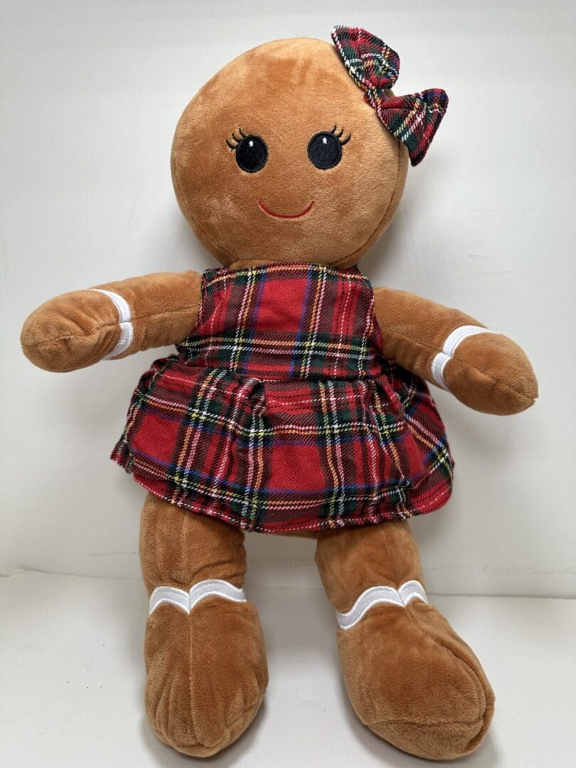 A stuffed gingerbread girl doll wearing plaid dress.