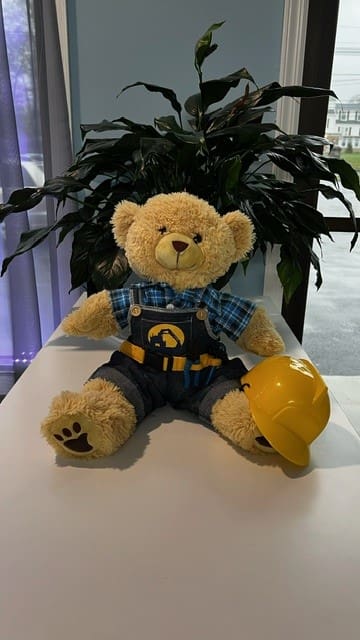 A teddy bear wearing a hard hat and overalls.